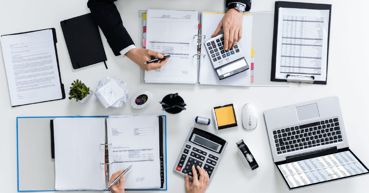 Top view of accountants working on a white table full of office documents