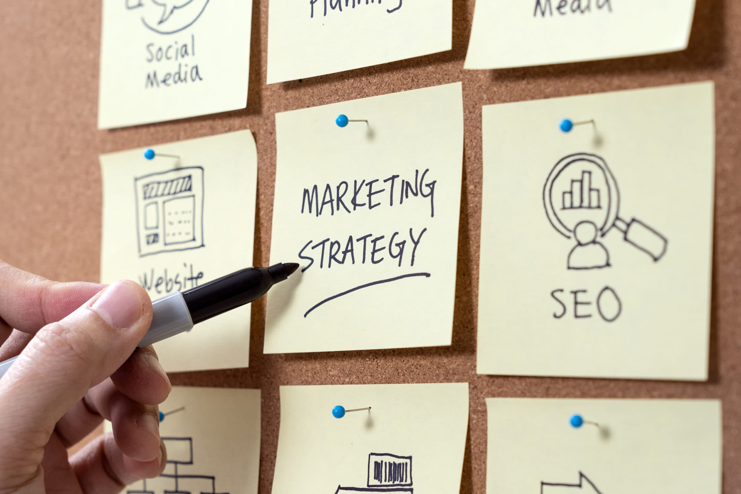 Close-up of a hand writing Marketing Strategy on a sticky note